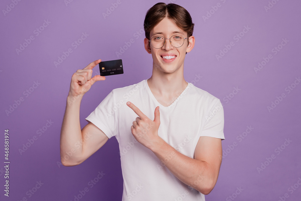 Photo of handsome cheerful man indicate finger credit card recommend advice choice isolated on violet color background Photo of handsome cheerful man indicate finger credit card recommend advice choice isolated on violet color background