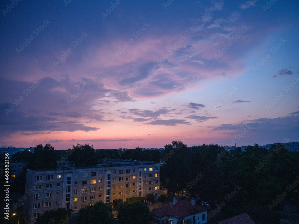 Fototapeta premium Dramatic red and dark blu clouds over city rooftops