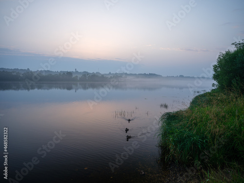 misty morning by the lake with calm water  fog and reflections of trees in mirror