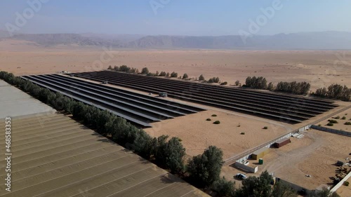 4K Birds Eye View of Solar Panels Farm or solar cell with sunlight. Small green energy Solar Farm field for producing alterative clean energy electric in the desert of Israel, Kibbutz Lotan next to photo