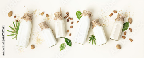 on dairy plant based milk in bottles and ingredients on light background. Alternative lactose free milk substitute, flat lay