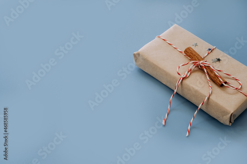 christmas and New Year blue background with space for text. gift box packed with craft brown paper. cinnamon stick and silver shiny stars