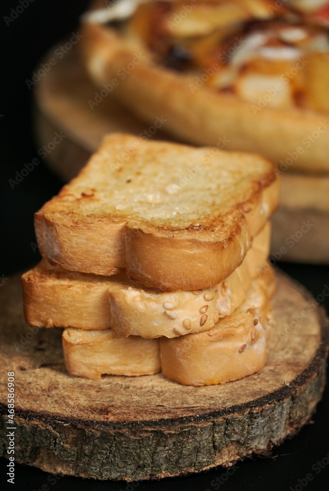 the close up view of a pile of toasted white bread on the wooden paddle. a shot of the western breakfast suitable for advertisement or presentation. the close up view of a pile of toasted white bread on the wooden paddle. a shot of the western breakfast suitable for advertisement or presentation.