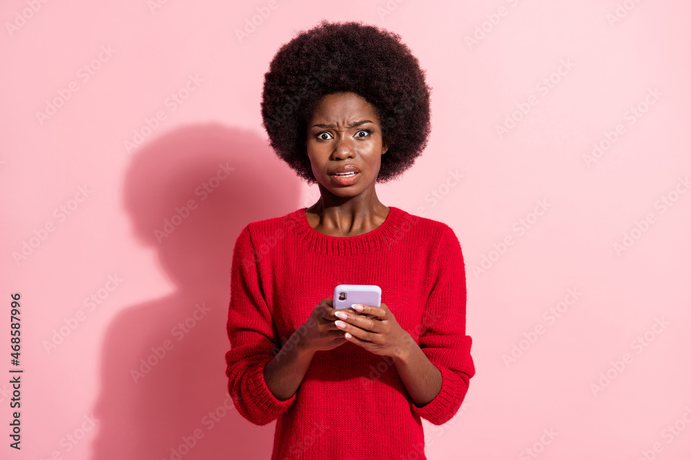 Photo of scared young afro american woman hold smartphone addicted user isolated on pink color background