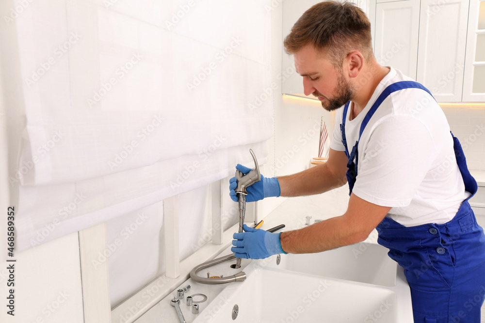 Professional plumber repairing water tap in kitchen Professional plumber repairing water tap in kitchen