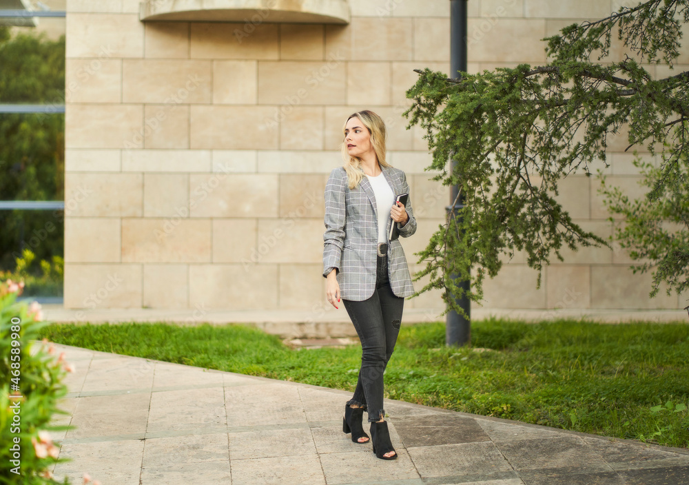 young businesswoman walking out of office with agenda in hand young businesswoman walking out of office with agenda in hand