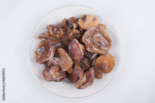 Frozen mushrooms close-up isolated on white plate, brown champignon prepared for cooking