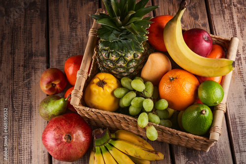 Fototapeta Naklejka Na Ścianę i Meble -  Mix of fresh juicy colorful exotic tropical fruits in basket on wooden background top view