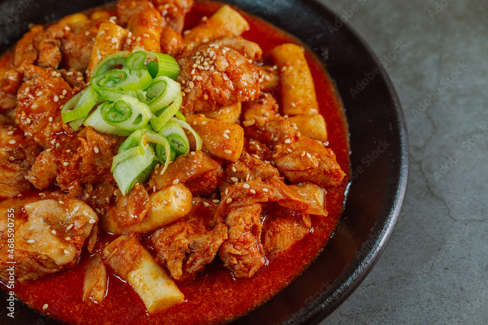 Korean food Spicy Stir-fried Chicken tteokbokki dish on black plate Korean food Spicy Stir-fried Chicken tteokbokki dish on black plate