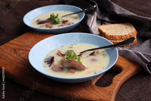 Creamy soup with boletus mushroom and herbs on wooden table
