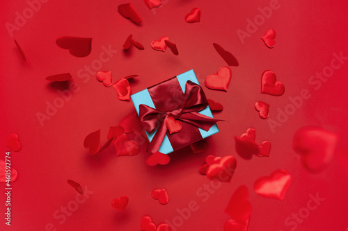 Valentines Day festive card, gift box with ribbon and satin hearts on red