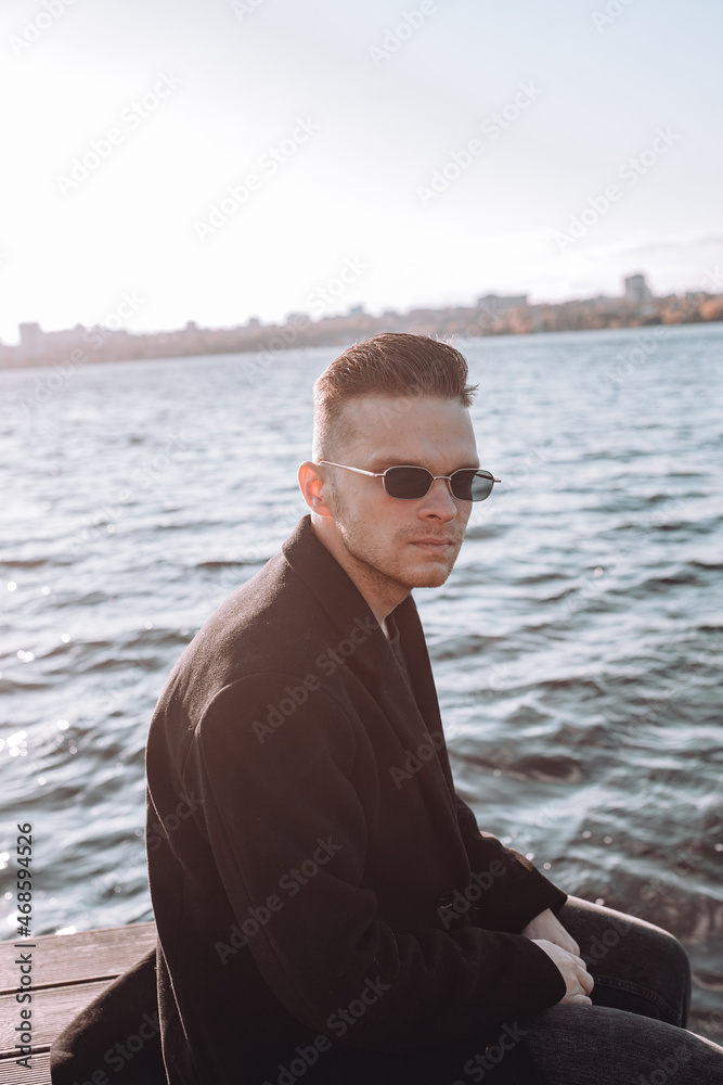 a young guy with a beard looks melancholically at the view of the lake a young guy with a beard looks melancholically at the view of the lake