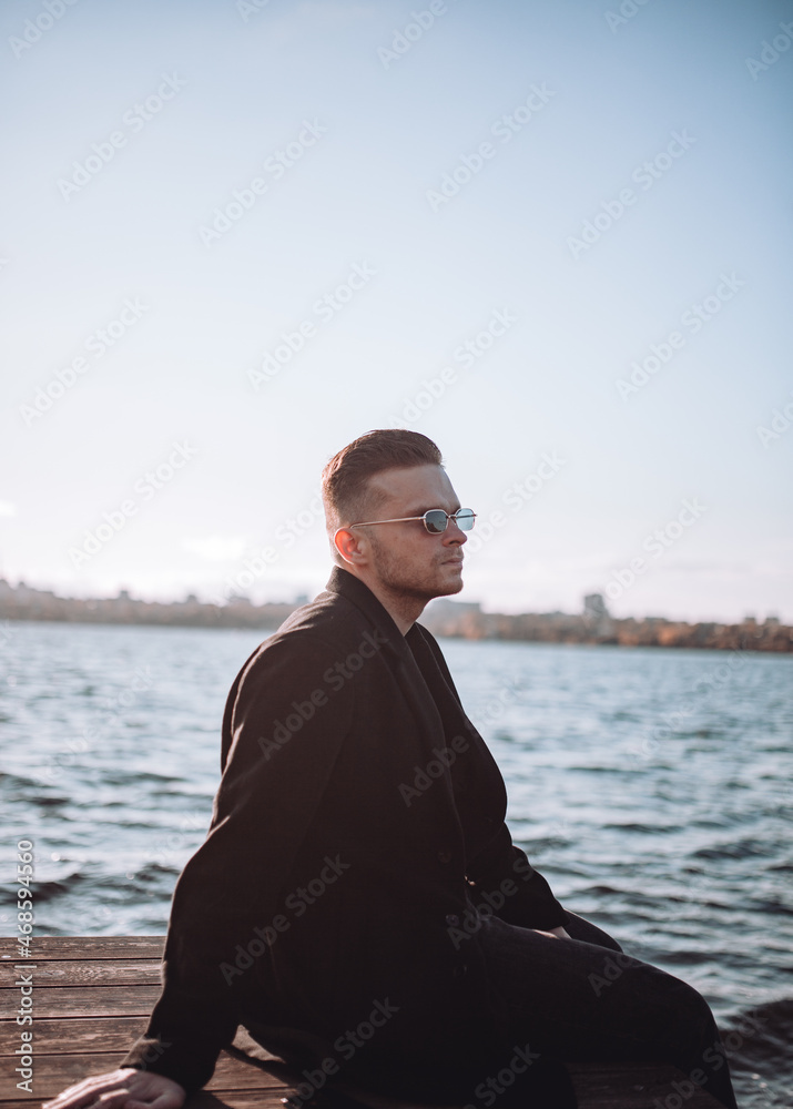 a young guy with a beard looks melancholically at the view of the lake a young guy with a beard looks melancholically at the view of the lake
