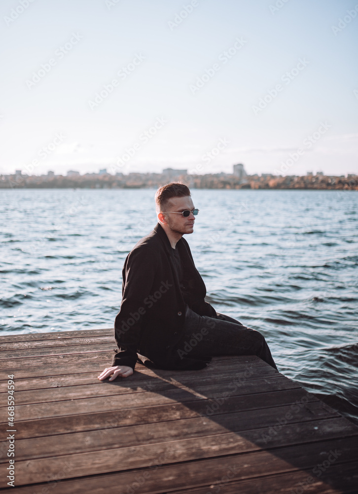 a young guy with a beard looks melancholically at the view of the lake a young guy with a beard looks melancholically at the view of the lake