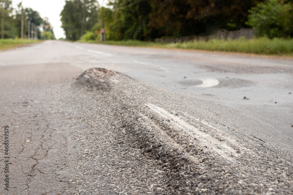 Road in terrible conditions with bumps on surface. Uneven road needs repairing Road in terrible conditions with bumps on surface. Uneven road needs repairing