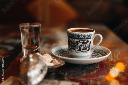 A cup of traditional black strong Turkish coffee  sweets delight and a small glass of water. Traditional drinks  coffee concepts.