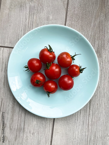Fresh vegetables: red cherry tomatoes on the blue plate. Top view.