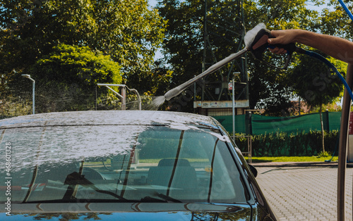 man's hand puts high pressure foam on the car