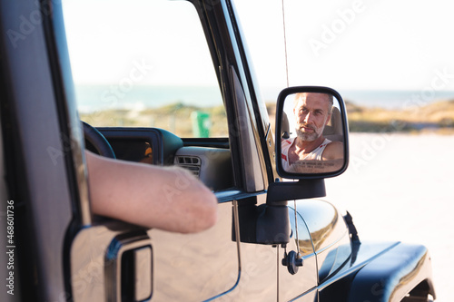 Wallpaper Mural Portrait of smiling caucasian man in car reflected in side mirror on sunny day at seaside Torontodigital.ca