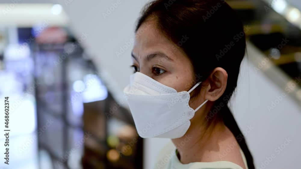 Asian female wear face mask standing on escalator in shopping center Asian female wear face mask standing on escalator in shopping center