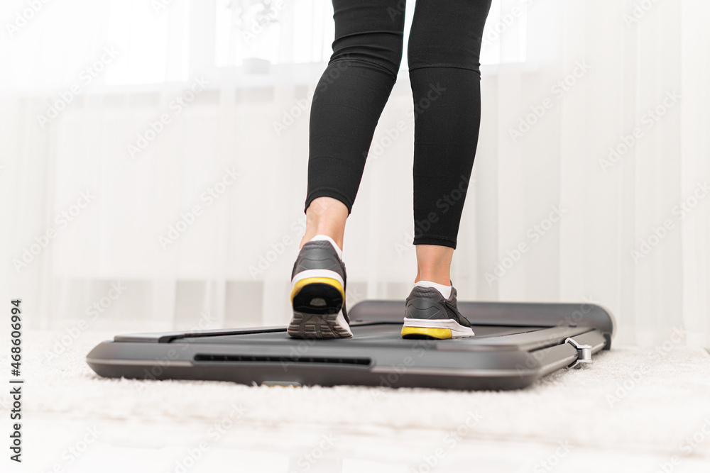 Sporty woman using walking treadmill in the interior of the room or home.