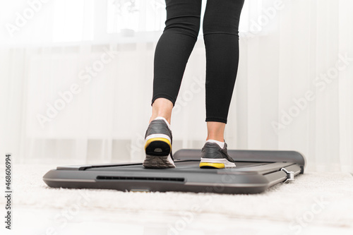 Obraz na płótnie Sporty woman using walking treadmill in the interior of the room or home. w salonie