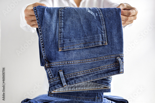 Woman folding blue jeans in pile photo