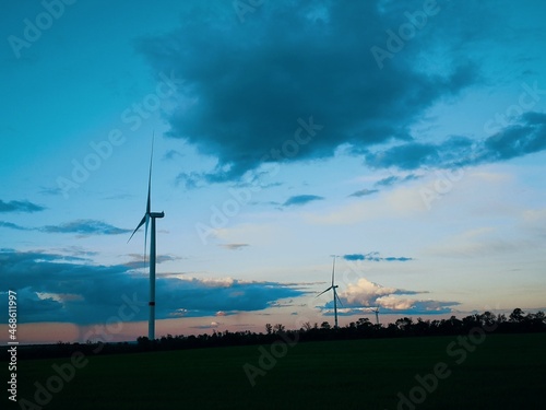 Windmills in the field at sunset against the background of the cloudy sky © Валерия Каретная