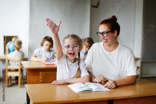 a teacher and a girl student, a child at school at a desk learning to read, a teacher and a student learn letters, working together with a teacher, with a tutor. Child and tutor in a lesson at school photo