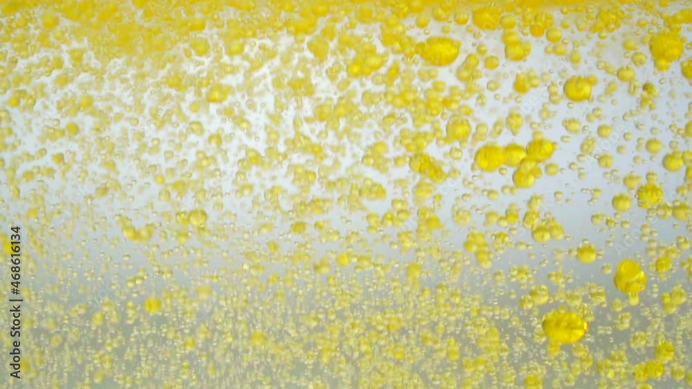 Oil background. Oil drops falling into water on a white background. Golden liquid drops in water. Oil background. Oil drops falling into water on a white background. Golden liquid drops in water.