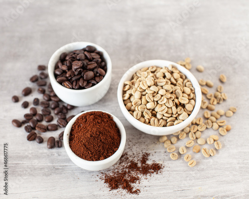 Green and brown unroasted and dark roasted coffee beans in white bowls