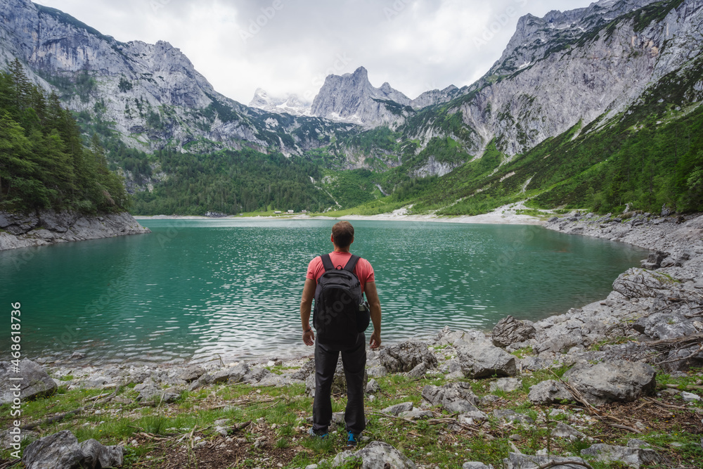 Man traveler enjoying view of Dachstein peak mountains on a Upper Gosau Lake. Gosau, Salzkammergut, Austria, Europe