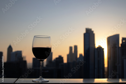 a glass of red wine on the background of the city at sunset