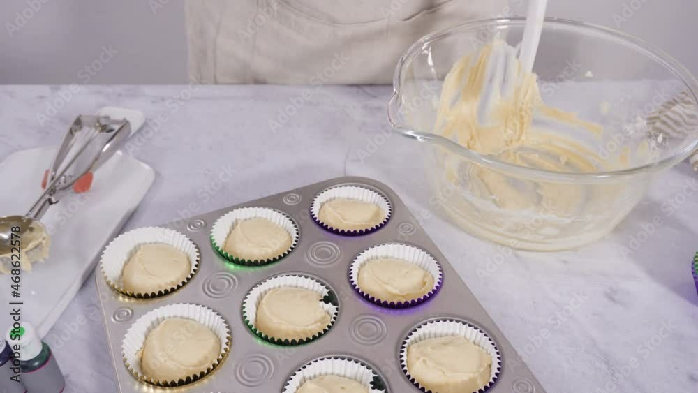 Step by step. Scooping cupcake batter into a foil cupcake liners to bake vanilla Mardi Gras