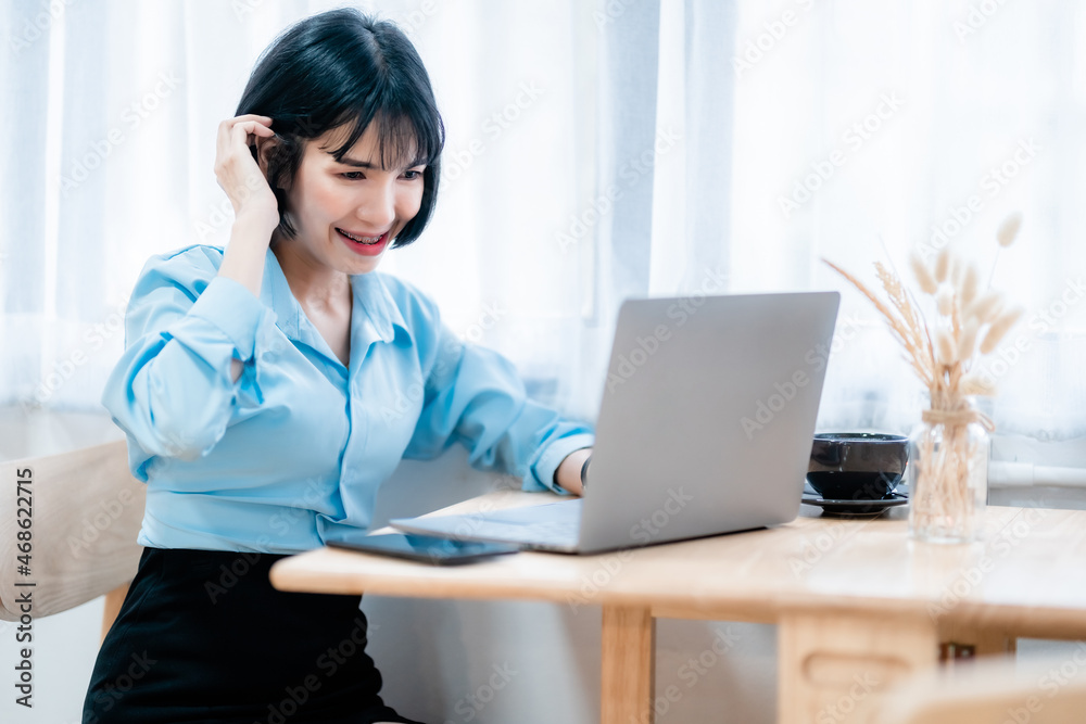 Smiling with dental braces of asian freelance people business female casual working with laptop computer and notebook with coffee cup and smartphone in cafe interior in coffee shop Smiling with dental braces of asian freelance people business female casual working with laptop computer and notebook with coffee cup and smartphone in cafe interior in coffee shop