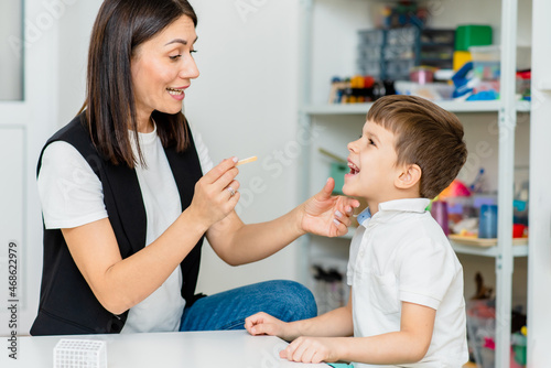 A little preschool boy is engaged in a speech therapist office and corrects his speech