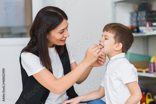 A little preschool boy is engaged in a speech therapist office and corrects his speech