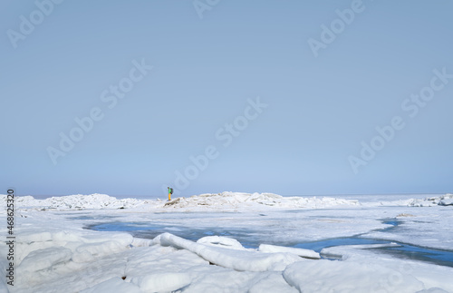 Young adult man with backpack outdoors exploring icy landscape