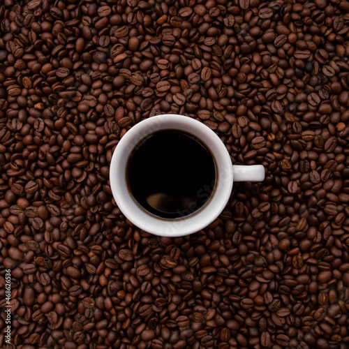 White Cup full of coffee. With a lots of beans around. Coffee background.