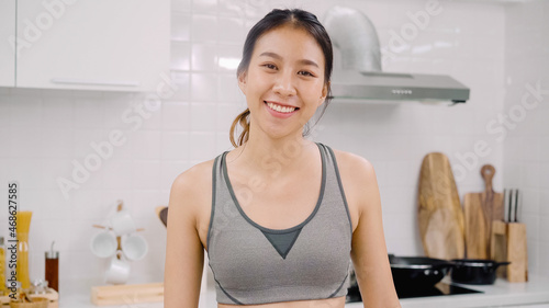 Portrait of young Asian blogger lady exercise and looking to camera in kitchen  Attractive beautiful indian female working out for healthy at home. Woman exercise at home concept.