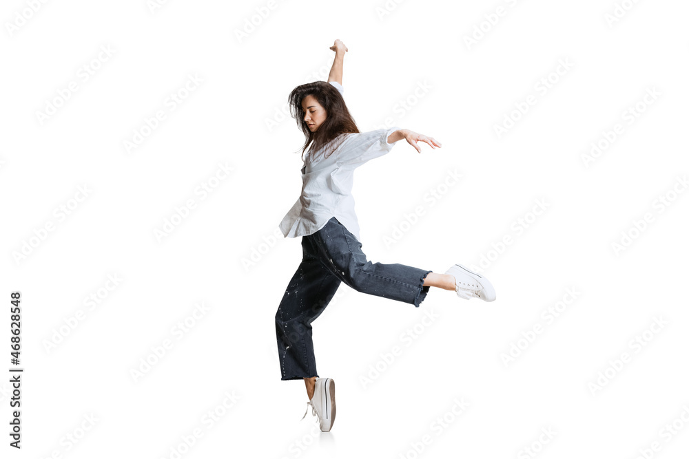 One beautiful emotive girl in casual wear moves dynamically isolated on white background. Art, motion, action, flexibility, inspiration concept.