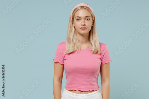 Valokuva Young serious calm beautiful caucasian blonde woman 20s wearing casual pink t-shirt headband looking camera isolated on plain pastel light blue background studio portrait
