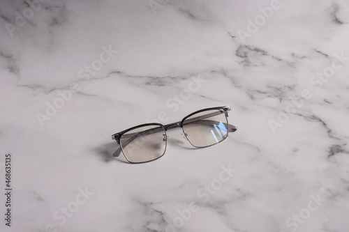 Glasses with blue light protection from computer and gadget radiation lie on a neutral gray background. Optical salon concept
