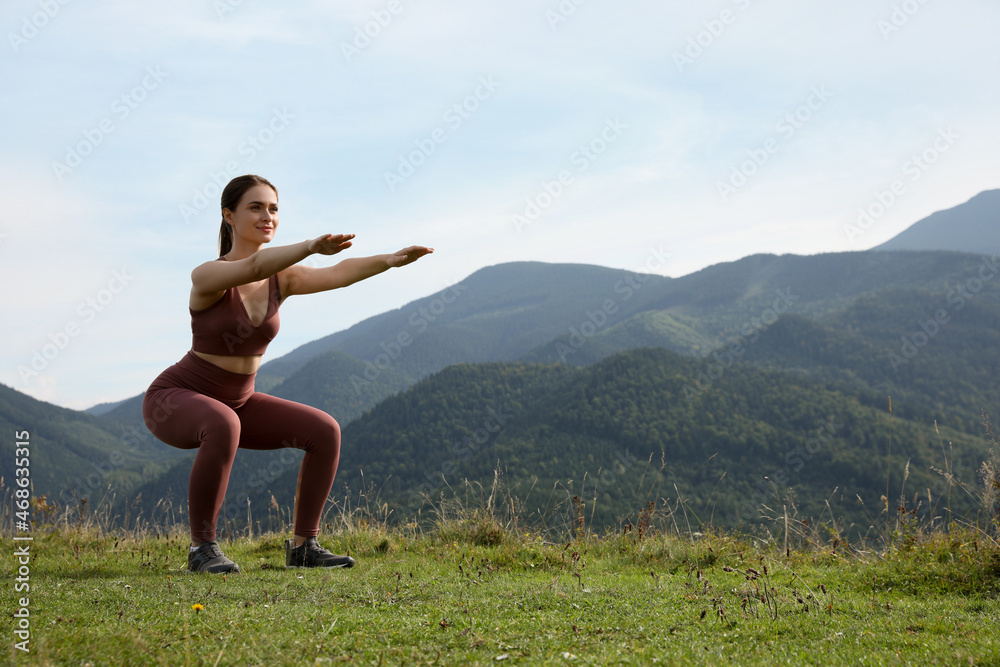 Young woman doing morning exercise in mountains, space for text Young woman doing morning exercise in mountains, space for text