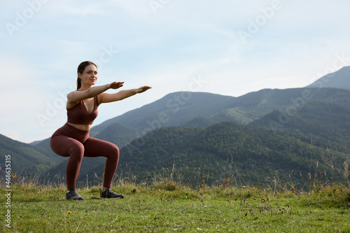 Young woman doing morning exercise in mountains, space for text