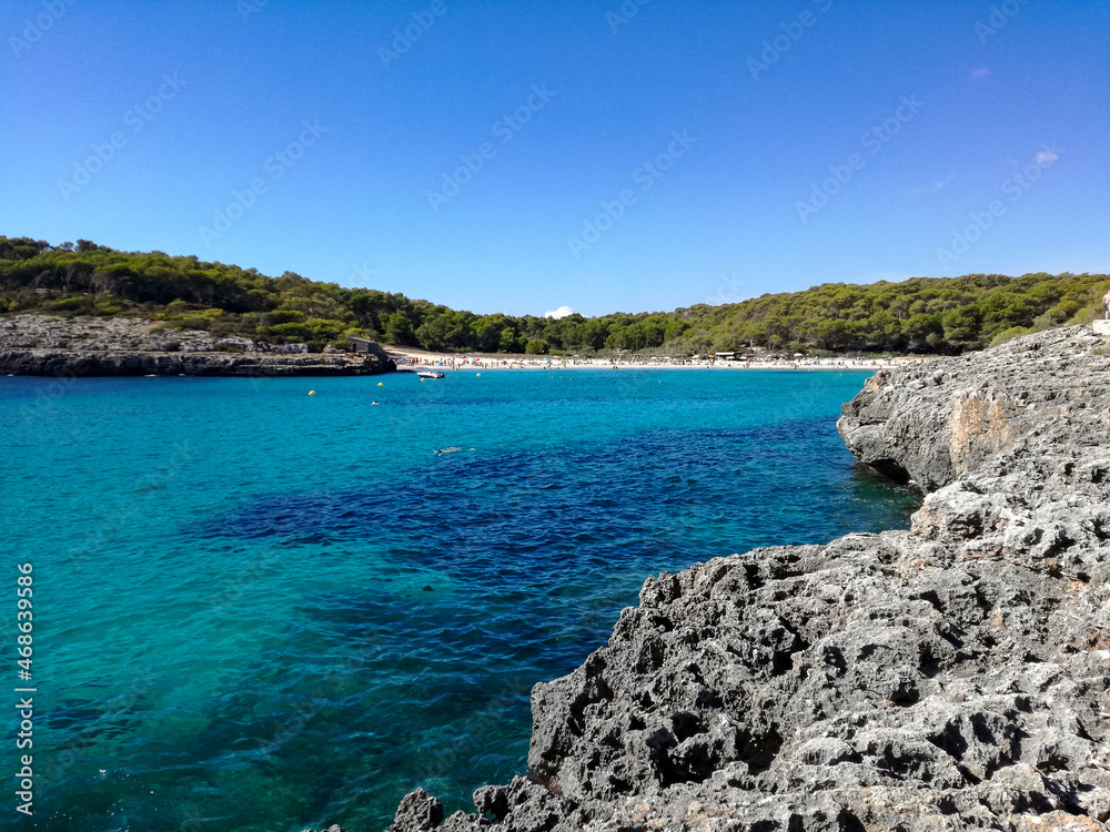 beautiful scene of a calm sea, under a blue sky with clouds and surrounded by a mountain with vegetation.