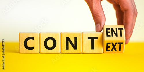 Content and context symbol. Businessman turns a wooden cube and changes the word context to content. Beautiful yellow table, white background. Business and content and context concept. Copy space.