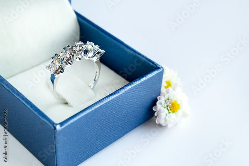 Elegant diamond ring in box with white daisy flower on white background © Betl