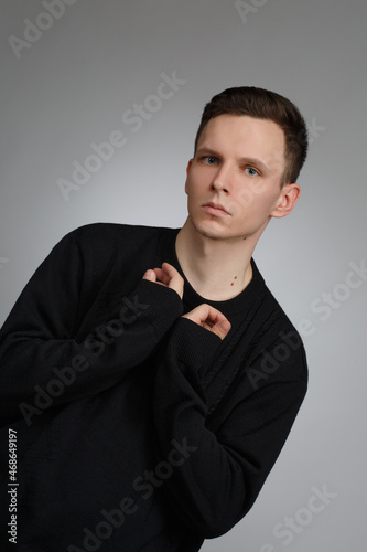 Young man in black sweater isolated on gray background.