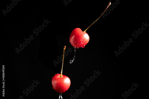 Collection of fresh cherries on a dark background, dynamic shot with action, splash, water drops and bokeh. Fresh fruit floating or levitating shotwith water droplet photo